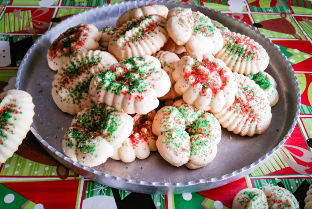 Cookie press almond spritz cookies on a metal pan.