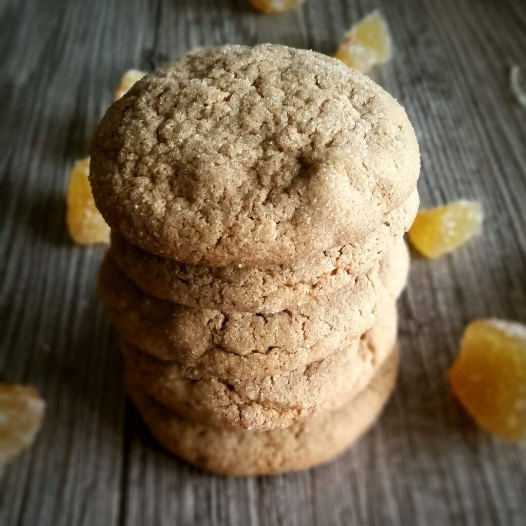 Stack of triple ginger cookies surrounded with ginger pieces.