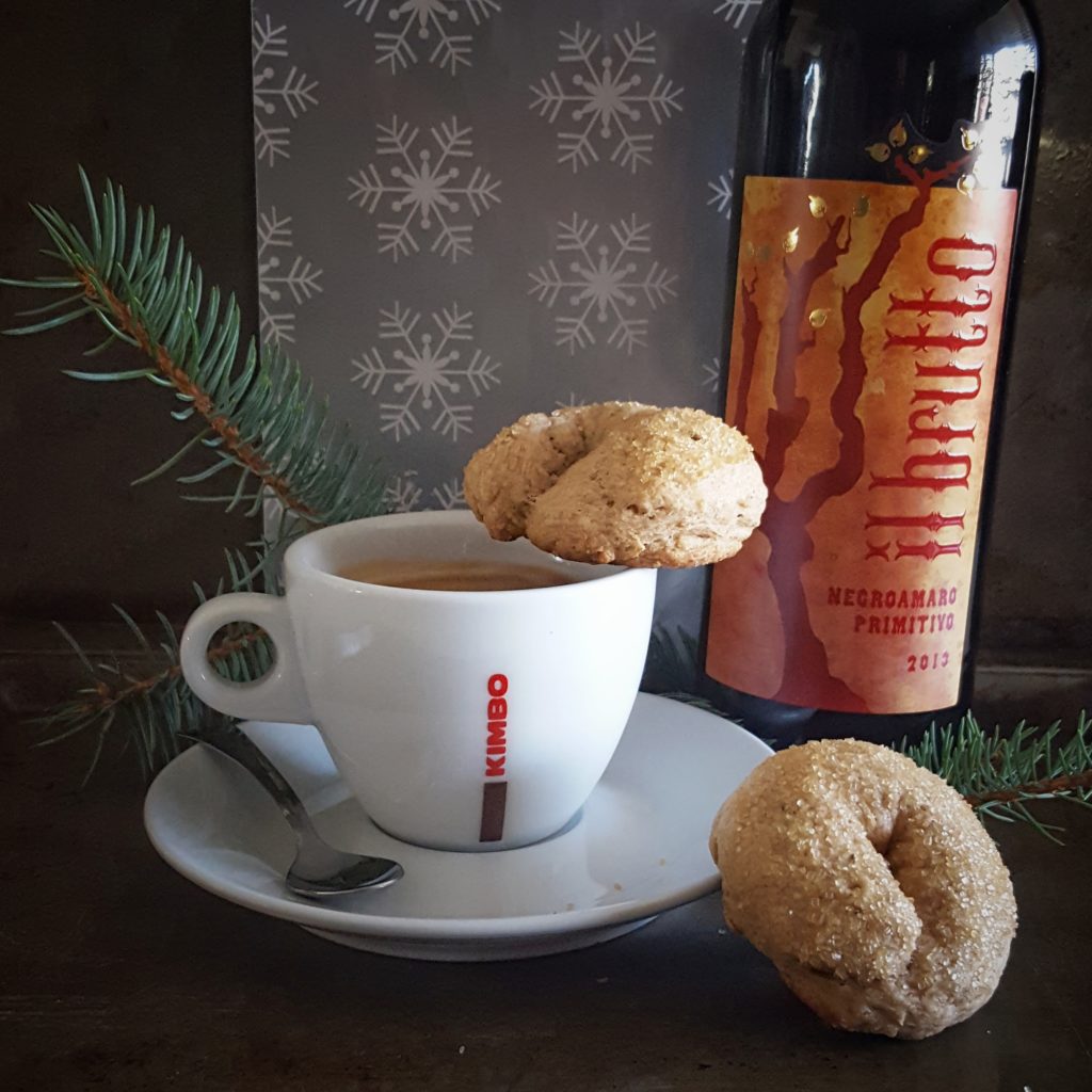 Hand dipping an Italian wine cookie into a glass of red wine the traditional Italian way