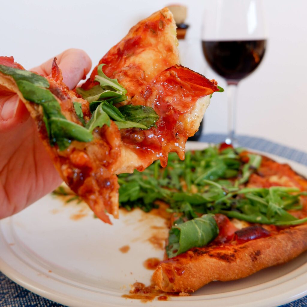 Presunto, goat cheese, arugula, and hot honey pizza on rustic board — made with authentic Italian pizza dough