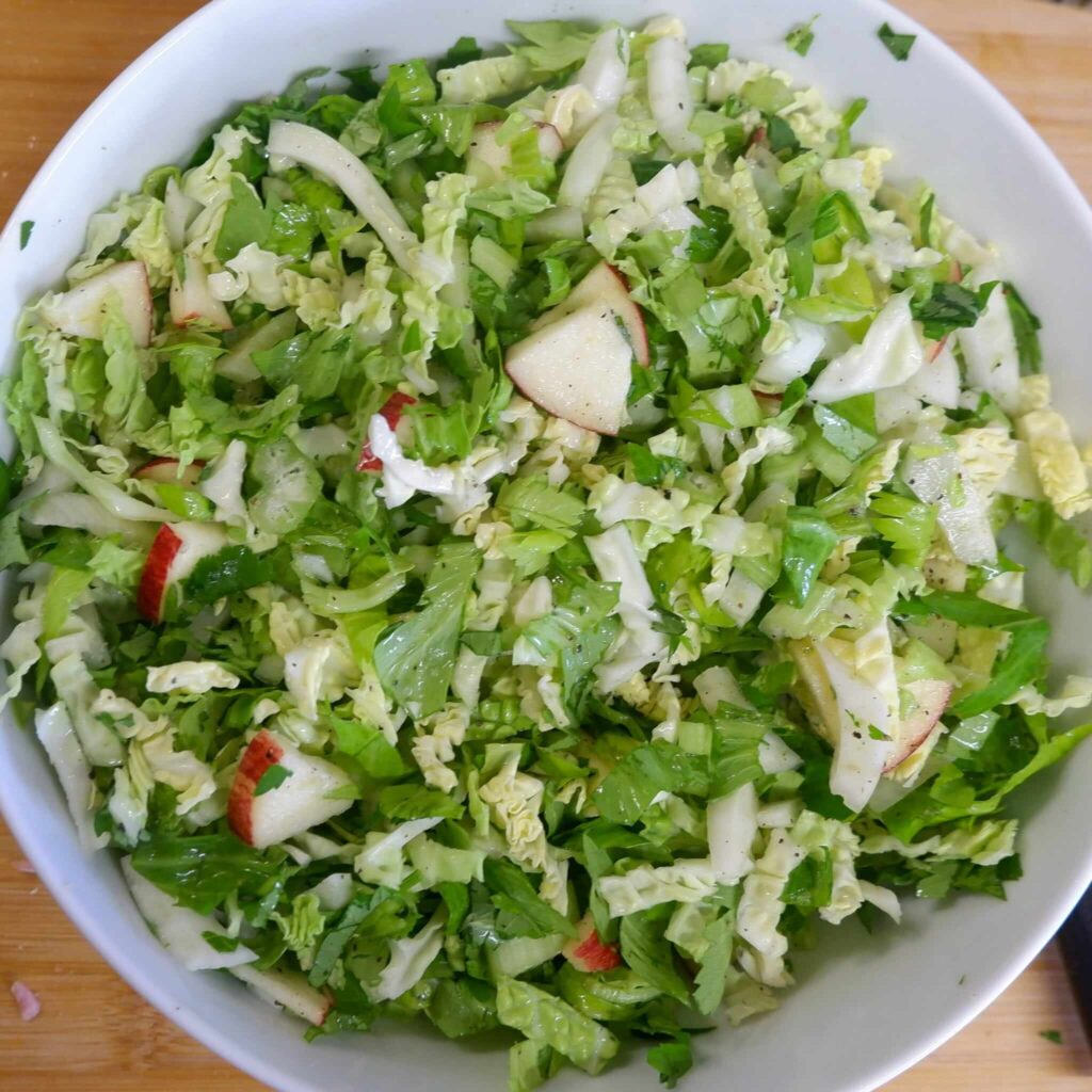 Crisp fennel apple cabbage slaw in a bowl, tossed with celery leaves, cilantro, lime, and pear white balsamic—bright, crunchy Portuguese-inspired mix.
