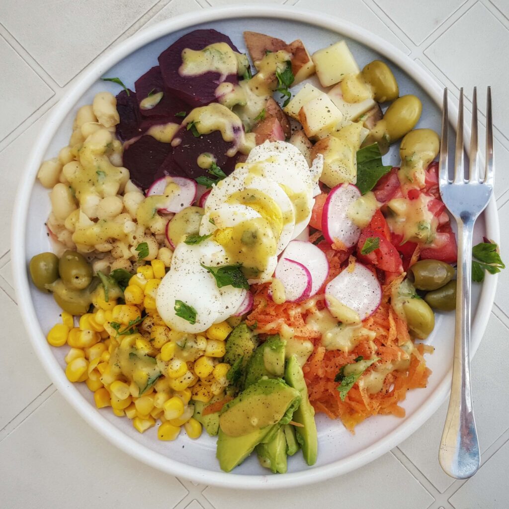 Fresh cilantro, sliced red onion and avocado arranged on top of Moroccan vegetable salad with lemon and olive oil dressing