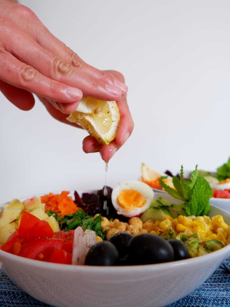 Hard boiled eggs sliced in half next to chickpeas and small diced potatoes for Moroccan salad bowl
