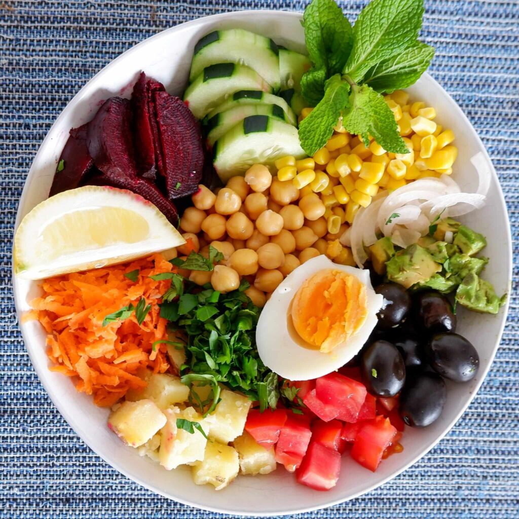 Close up of Moroccan salad with all ingredients arranged in rainbow sections on plate showing colors and textures