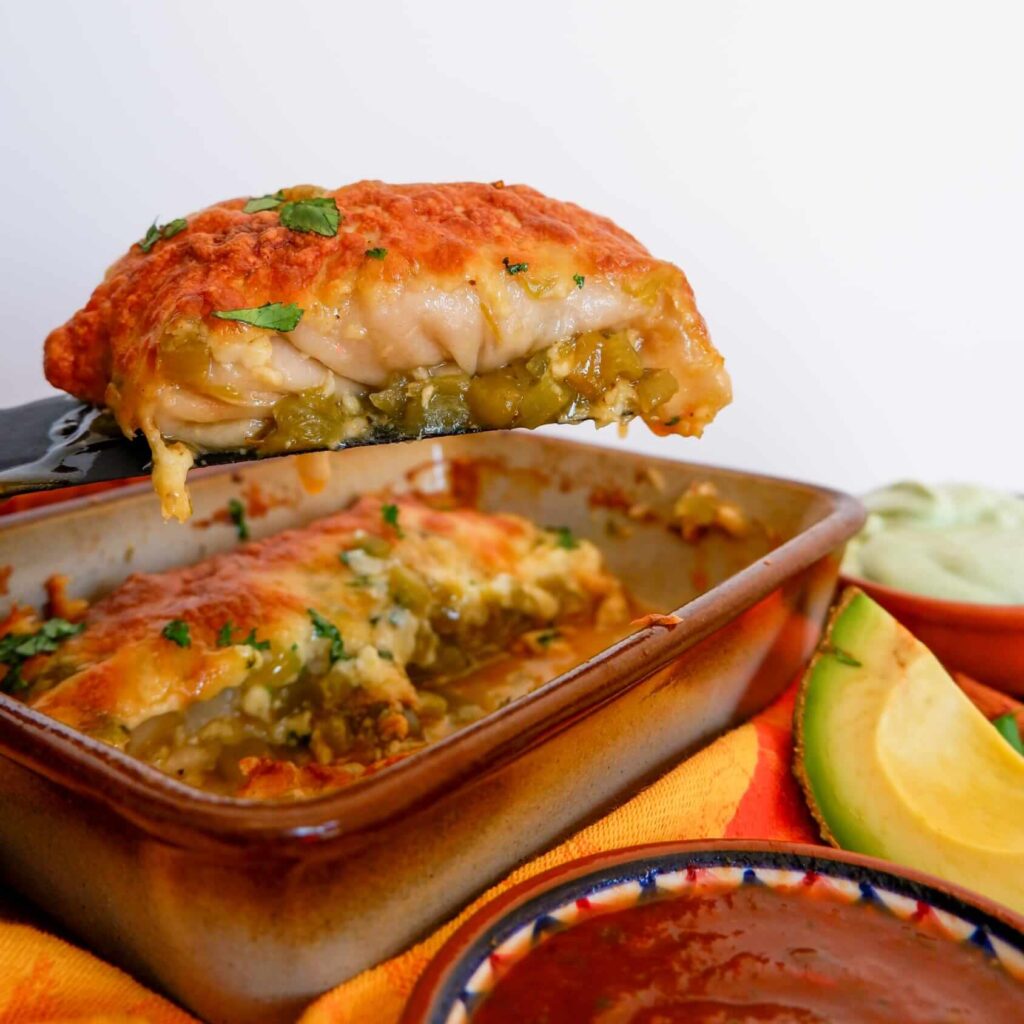 Green chile chicken enchiladas topped with avocado crema, salsa, and fresh cilantro