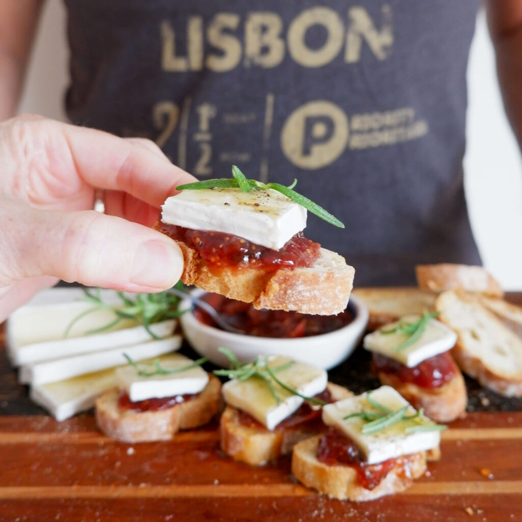 A tray of fig and brie crostini on broiled baguette slices drizzled with balsamic and hot honey