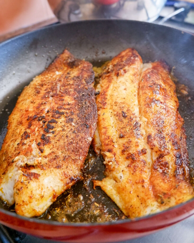 Golden seared fish fillet resting in a skillet after cooking