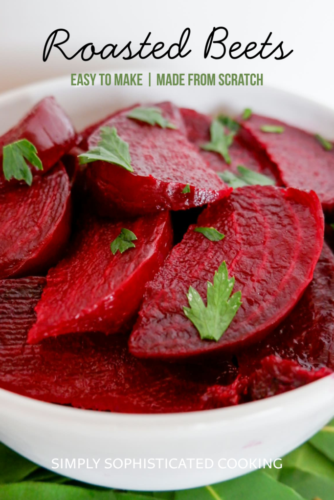 Close-up of oven roasted beet wedges garnished with fresh parsley leaves in a white bowl set on fresh bay leaves — how to roast beets recipe