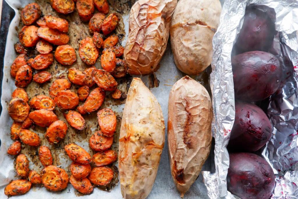 Just opened foil packet of beets on a parchment-lined baking sheet with sweet potatoes, carrots, and garlic bulbs