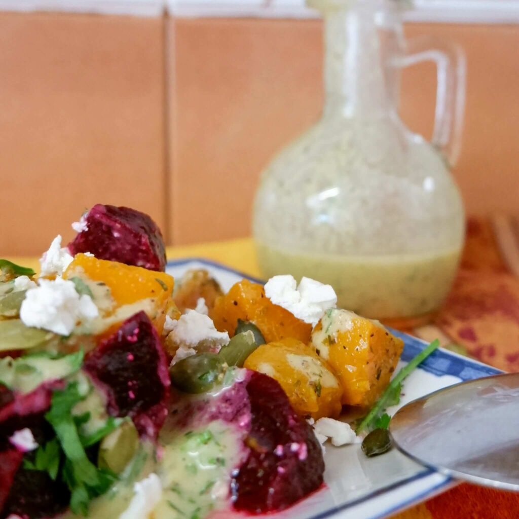 Roasted beet and butternut squash salad drizzled with lime Dijon vinaigrette on a holiday table